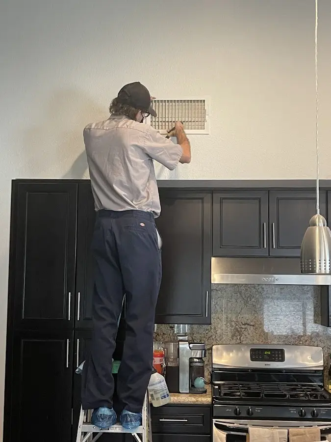 Technician inspecting an air vent during HVAC service in Wells Branch